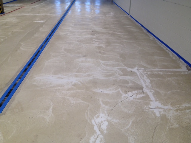 Commercial epoxy floor mid-installation at a dealership service area